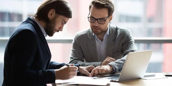 Two businessmen reviewing documents in an office setting.