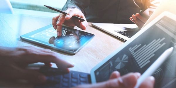 People analyzing data on tablets and laptop in a business meeting.
