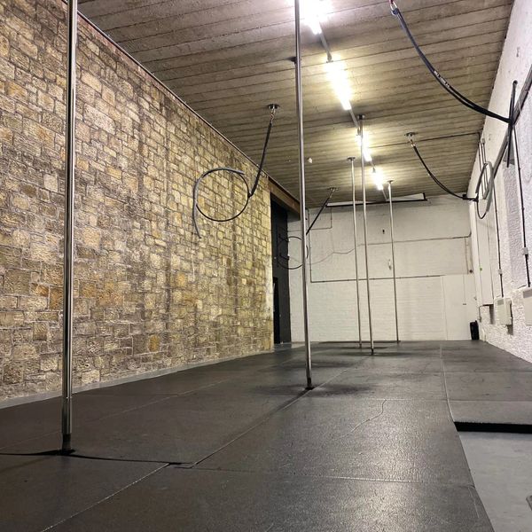 Empty dance studio with poles and exposed brick wall.