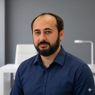 Man with a beard and blue shirt sitting in an office.
