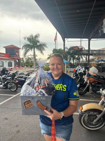 Smiling woman holding a gift basket at a motorcycle event.
