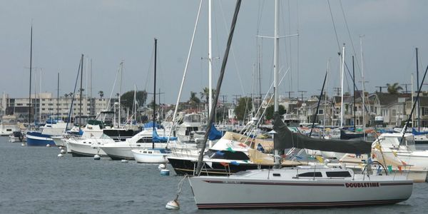 Docked sailboats and yachts at a marina on a cloudy day.