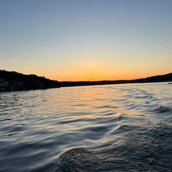 Calm water at sunset with orange and blue sky.