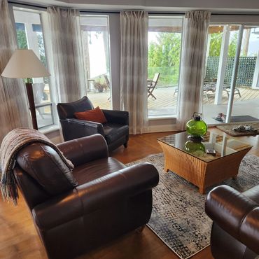 Cozy living room with leather chairs and large windows.