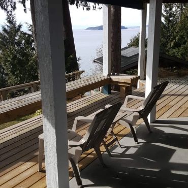 Wooden porch chairs overlooking a scenic water view.