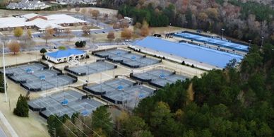 Aerial view of multiple tennis courts and surrounding buildings.
