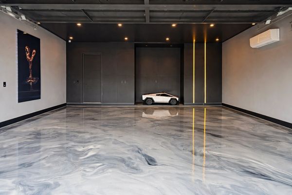 Metallic epoxy floor installed in modern garage with cabinets.