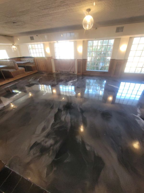 Dark and mid grays marbled floor reflecting windows and lights in a bright room.