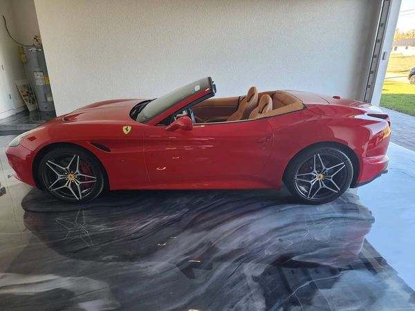 Red Ferrari parked on marble-effect metallic epoxy garage floor in Cape Coral, Florida.