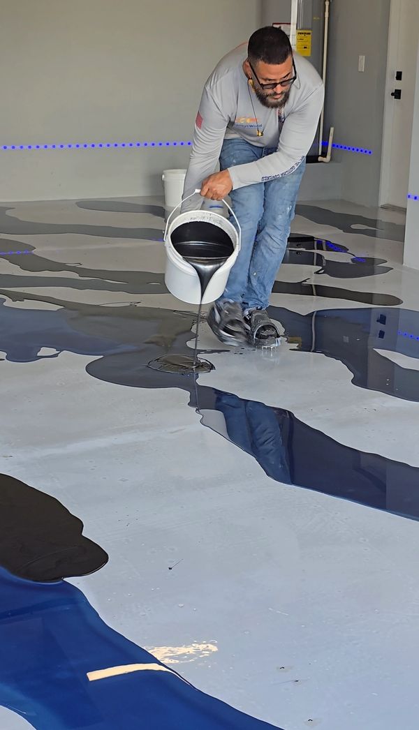Metallic epoxy floor installation in progress, resin being poured.