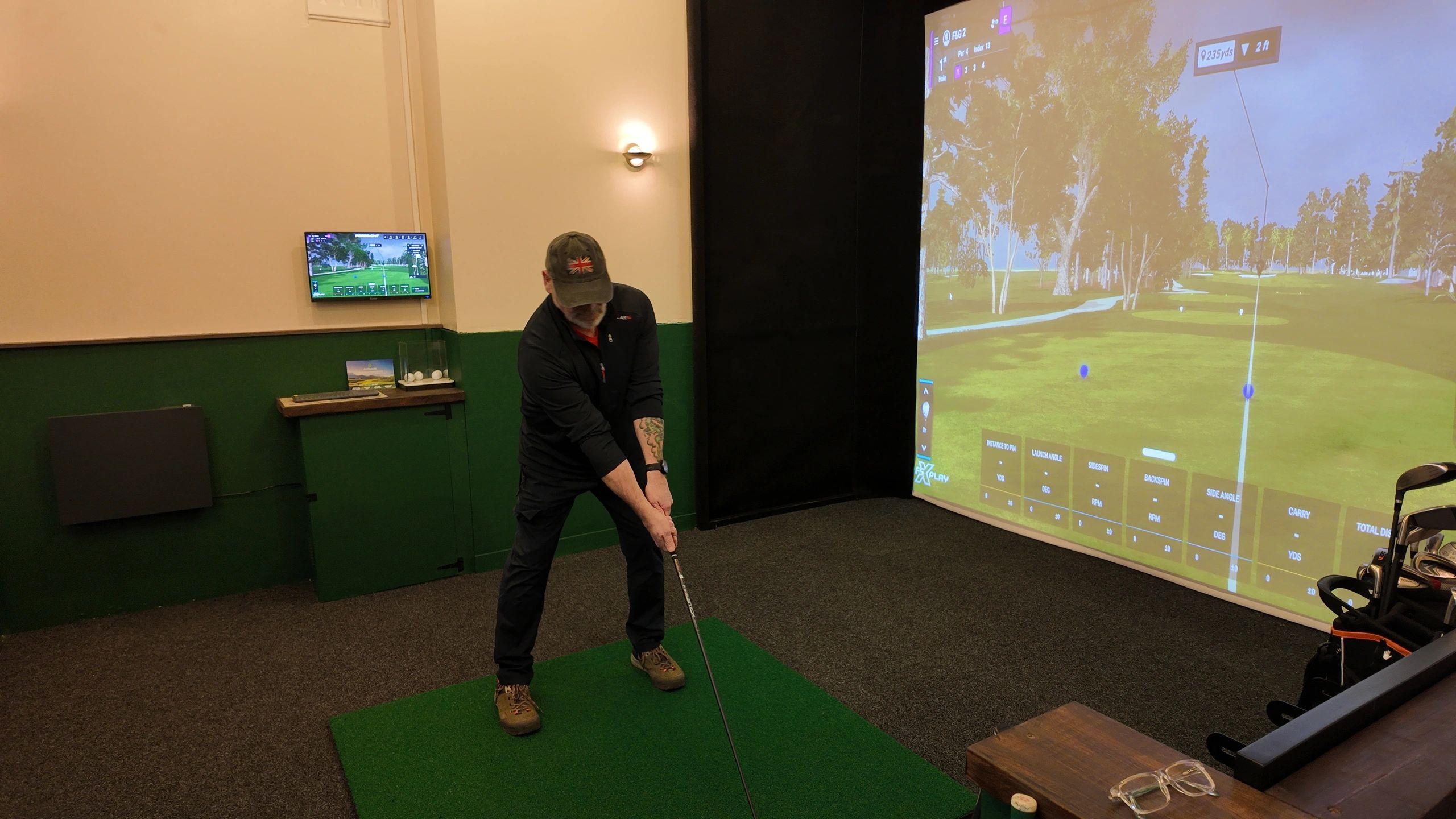 Man practicing golf indoors with a simulator screen.