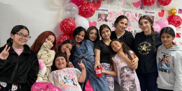 A group of smiling girls posing together at a decorated party.