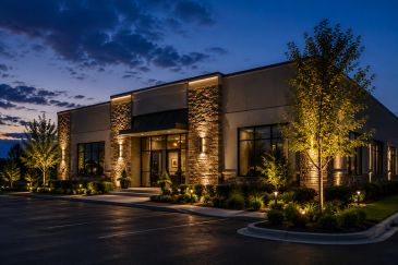 A modern building illuminated by warm lights at dusk.