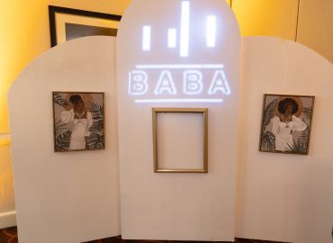 Art display with two portraits and a central frame under 'BABA' sign.