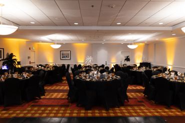 Elegant banquet hall with round tables and black chairs.