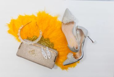 Silver high heels, chain purse, and orange feather fan.