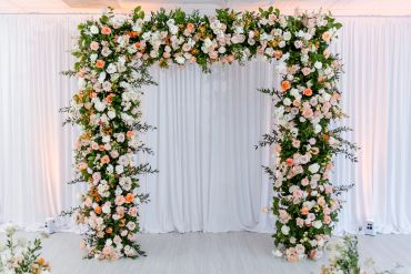 Floral wedding arch with white and peach flowers.