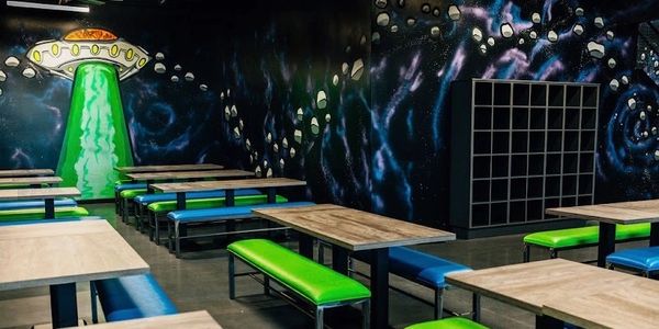 Colorful space-themed cafeteria with alien spaceship mural and vibrant seating.