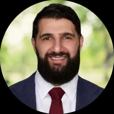 Smiling man in suit and red tie with beard.