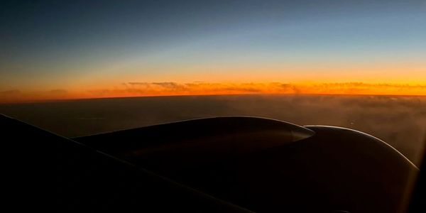 Sunset view from an airplane window showing the wing and engine.