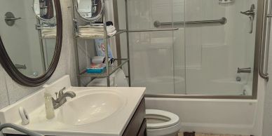 Clean bathroom with sink, mirror, toilet, and glass shower.