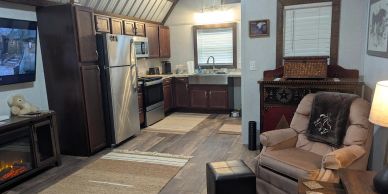Cozy kitchen and living area with wooden cabinets and recliner.