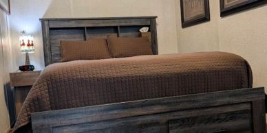 Cozy bed with brown bedding in a rustic wooden frame.