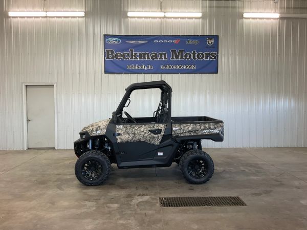 A camouflaged utility vehicle inside a garage with Beckman Motors signage.