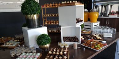 Elegant buffet table with assorted mini sandwiches, desserts, and drinks.