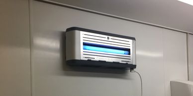 Insect zapper with blue light on a wall.