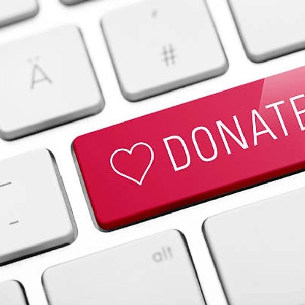 Red "Donate" key with heart icon on a white keyboard.