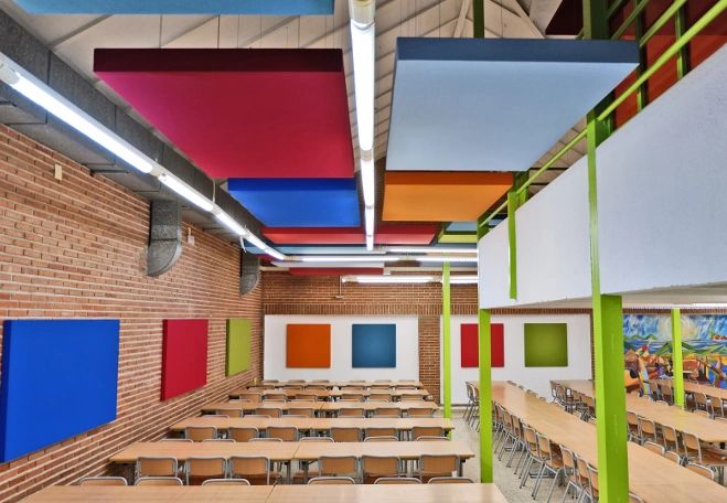 Colorful panels adorn the ceiling and walls of a modern classroom with rows of desks.