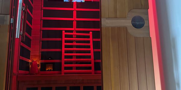 Interior view of a sauna with red lighting and wooden paneling.
