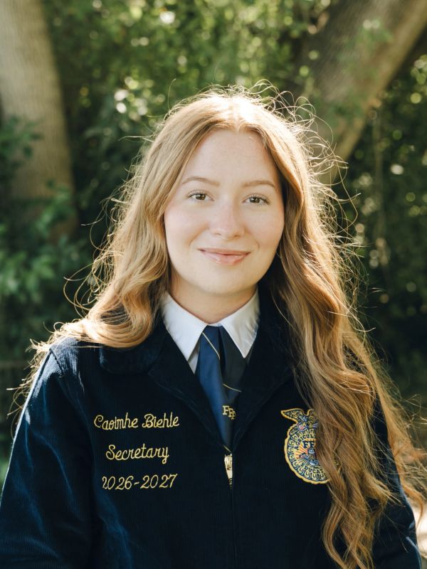 Young woman in FFA jacket smiling outdoors.