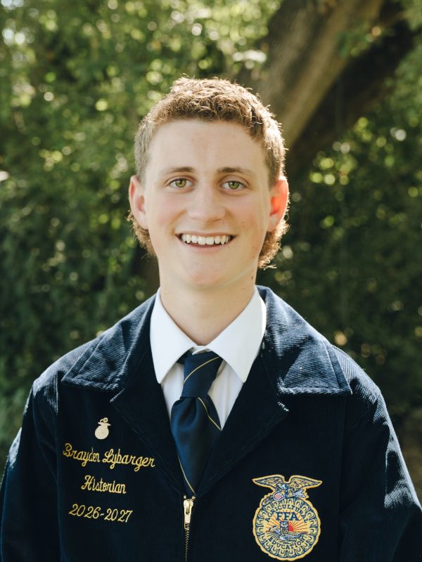 Young man in FFA jacket smiling outdoors.