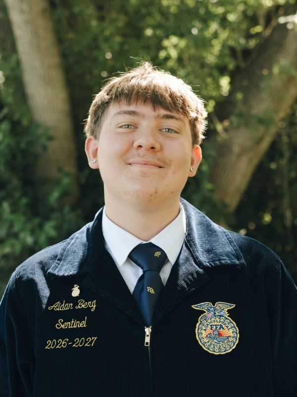 Young man in a blue FFA jacket smiling.