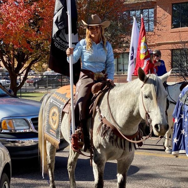 Alexis Mcquarie of Low Arrow Performance Horses riding a Gray Horse at local parade. 
