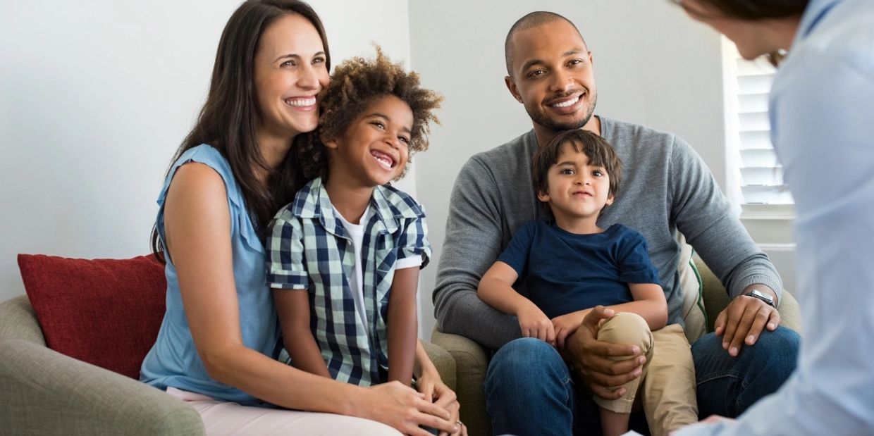 A happy family of four sitting together and smiling during a conversation.