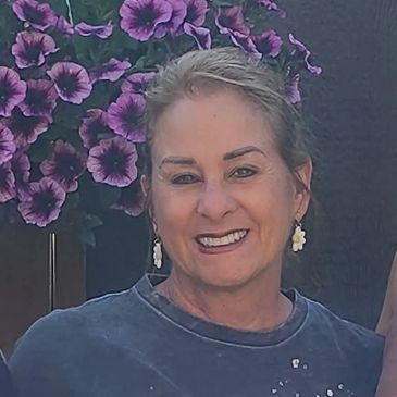 Smiling woman with purple flowers in the background.