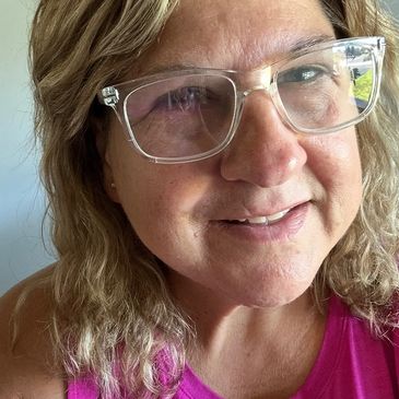 Smiling woman with glasses and wavy hair.