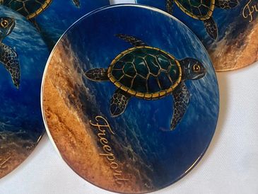 Round coasters with a sea turtle design and the word 'Freespirit'.