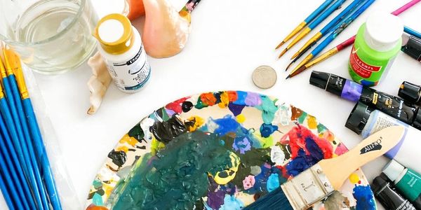 Colorful artist palette surrounded by paintbrushes and acrylic paints.