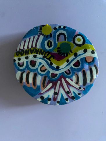 Colorful painted round stone with abstract patterns and dots.