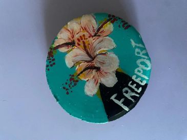 Hand-painted floral design on a circular object with 'Freeport' text.