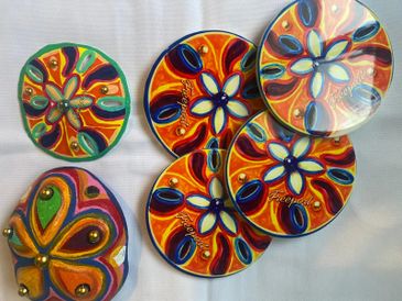 Colorful, hand-painted ceramic coasters and a matching holder with floral designs.