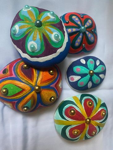 Colorful hand-painted stones with floral patterns and bead embellishments.