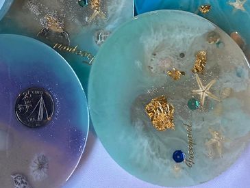 Decorative resin coasters with embedded sea-themed elements and gold flakes.