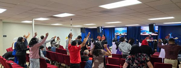 People raising hands during a lively church service with music.
