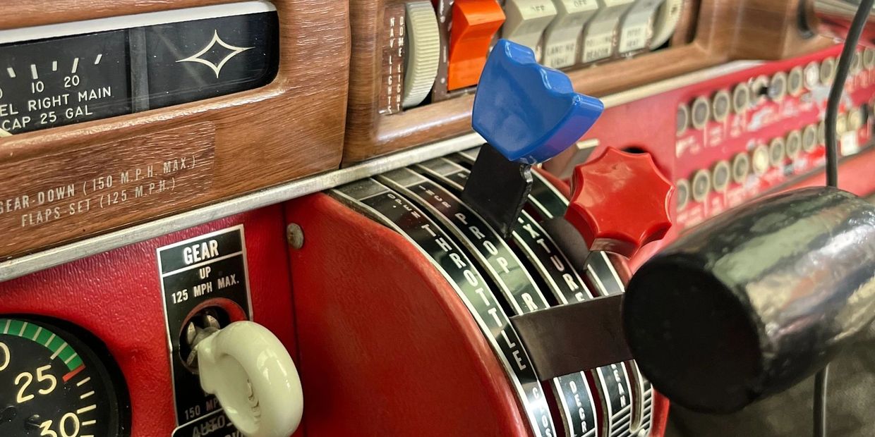 Close-up of aircraft throttle and propeller controls with colorful knobs.