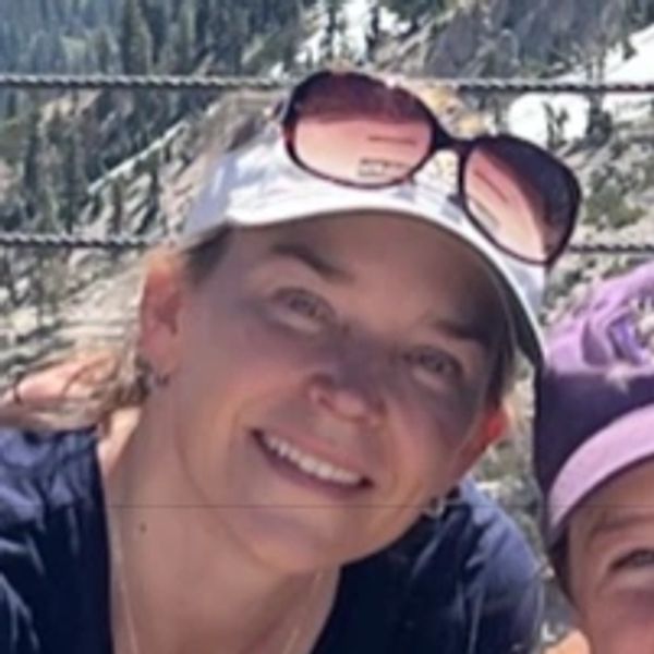 A picture of Cindra, a white woman with brown hair smiling at the camera